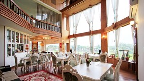 Un vaste espace dédié à la salle à manger, agrémenté de meubles blancs élégants et d’un tapis rouge à motifs.