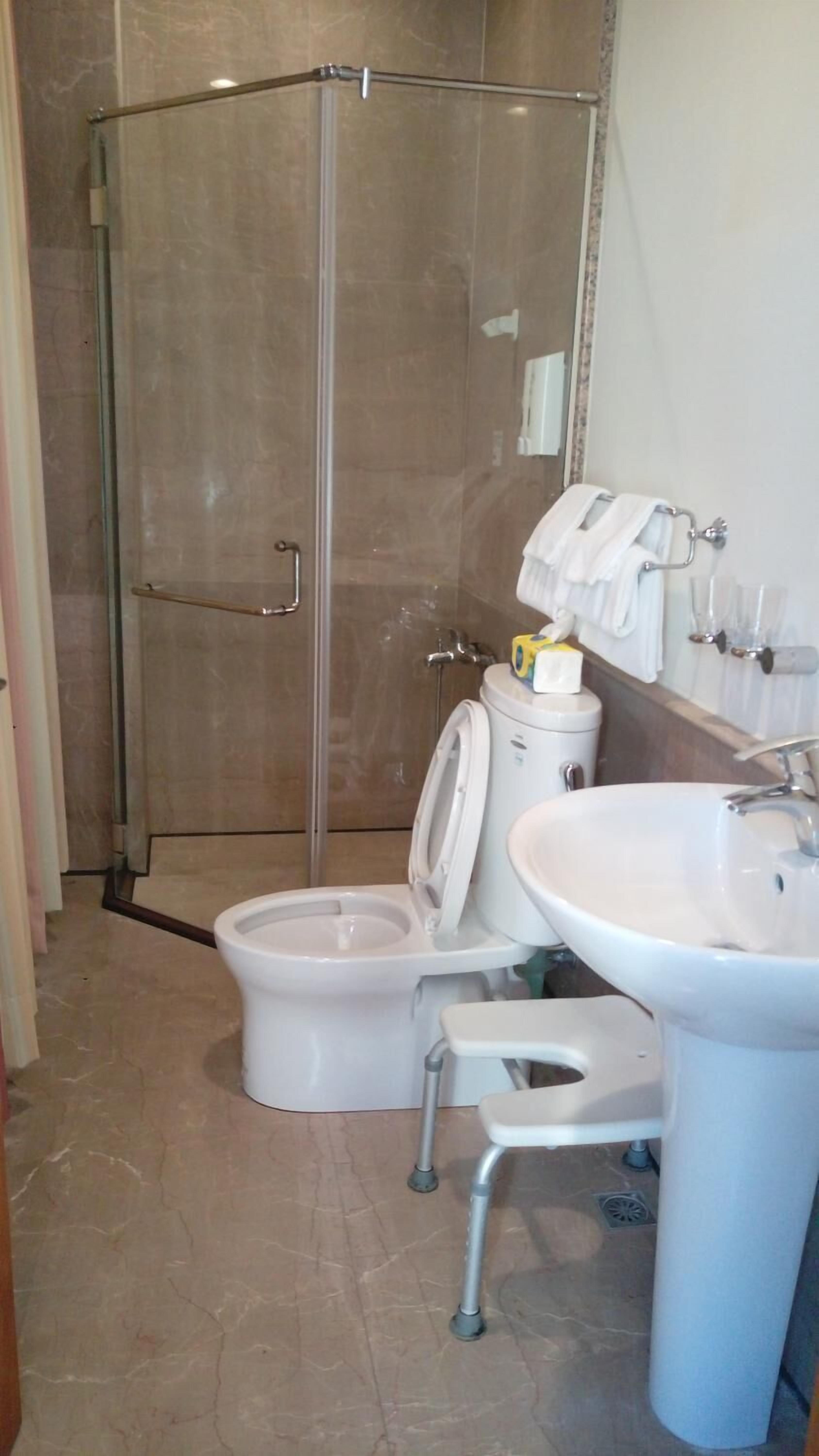 Kylpyhuone, jossa on lasiseinällä varustettu suihku, wc ja pesuallas.