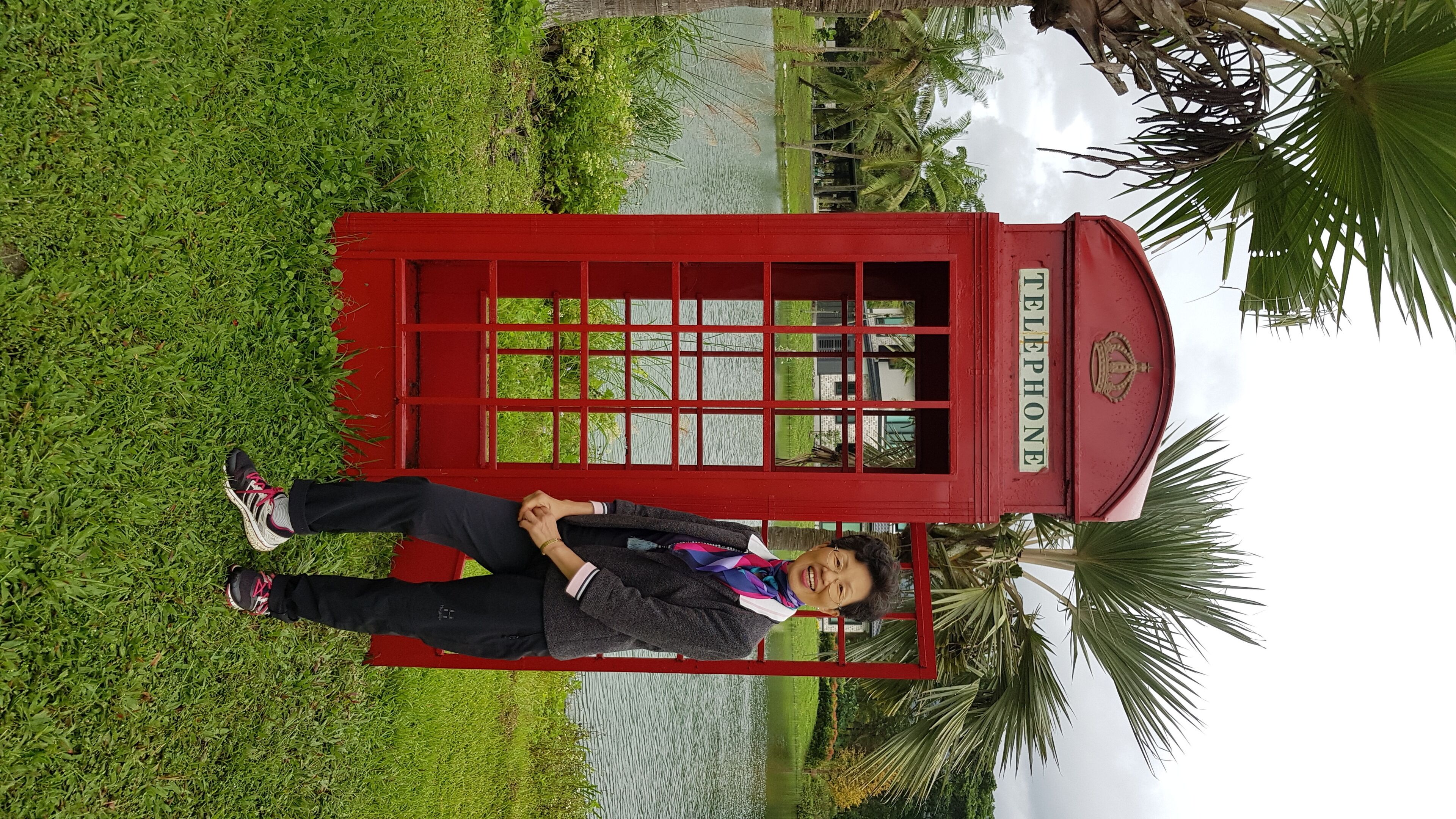 A person standing in front of a red telephone booth with the word "TELEPHONE" on it.