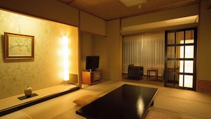 A traditional Japanese room with tatami flooring, a low table, a television, and sliding doors. - Atami New Fujiya Hotel (Atami)