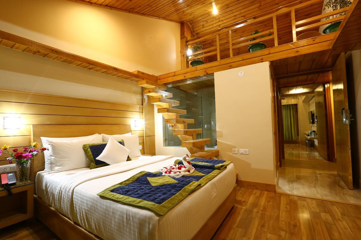 A bedroom with a wooden staircase, a bed with a quilt, and a nightstand with a vase of flowers.