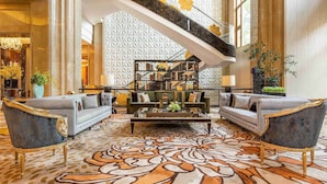 A spacious lobby with a grand staircase, two sofas, a coffee table, and a patterned carpet. - Chateau Star River Shaanxi (Xianyang)