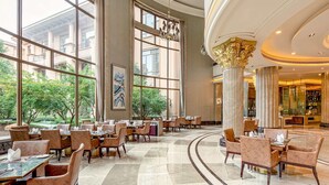 A spacious hotel lobby with large windows, elegant chandeliers, and a central column. - Chateau Star River Shaanxi (Xianyang)
