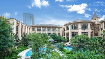 Relax by the pool surrounded by lush greenery and classical architecture.