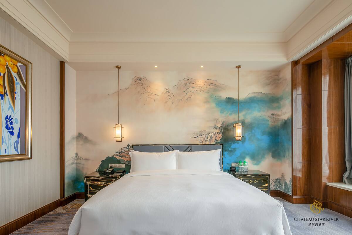 Een hotelkamer met een groot bed, een wanddecoratie en een nachtkastje met een lamp.