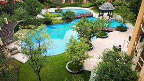 A large outdoor swimming pool surrounded by lush greenery, a gazebo, and a covered seating area. - Chateau Star River Shaanxi (Xianyang)