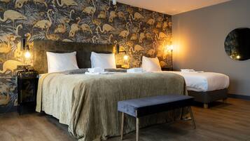 A hotel room with a large bed, a bench, and a wall with a tropical wallpaper.