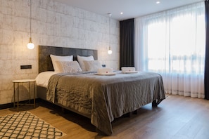 A modern bedroom with a large bed, a small side table, and a hanging light fixture. - Boutique Suites Lisse - Keukenhof (Lisse)