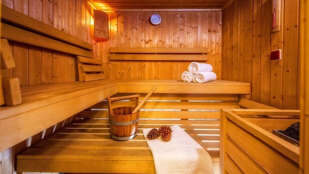 A wooden sauna with benches, a wooden bucket, and towels. - Rezydencja Sienkiewiczówka (Zakopane)