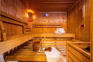 A wooden sauna with benches, a wooden bucket, and towels. - Rezydencja Sienkiewiczówka (Zakopane)