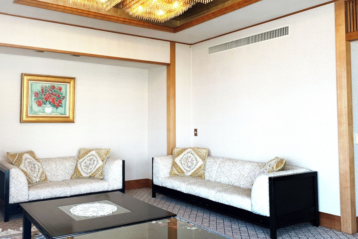 A living room with two sofas, a coffee table, a painting, and a small table with a lamp.