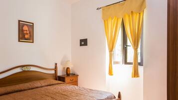 Um quarto com uma cama de madeira, uma mesa de cabeceira com abajur e uma janela com cortinas amarelas.
