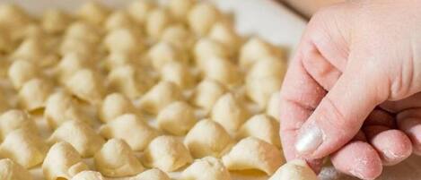 A hand placing a dough ball on a floured surface.