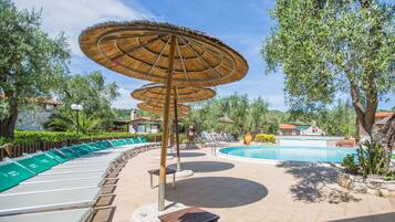 A poolside area with lounge chairs, a swimming pool, and thatched umbrellas.