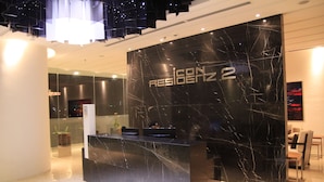 Un moderno mostrador de recepción con acabado de mármol y el texto "RESIDENCE 2" en la pared de fondo.