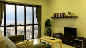 Una sala de estar con sofá, una mesa de centro, televisor y estantería.