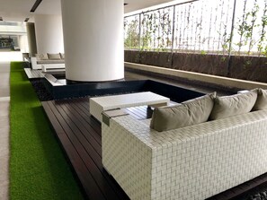 A modern outdoor seating area with a white patterned sofa, a small table, and a bench.