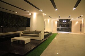 Un moderno hall con un sofá blanco, una pequeña mesa de centro y un camino de césped artificial verde.