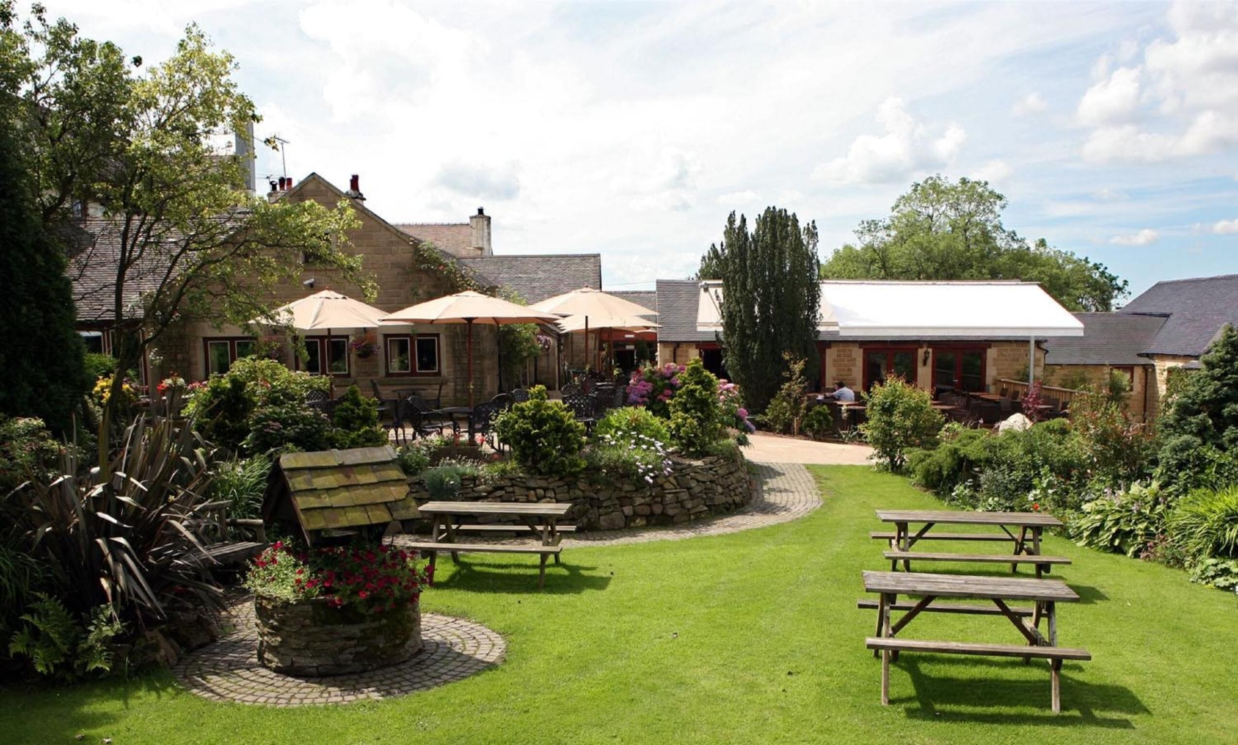 A courtyard with outdoor seating, stone planters, and a stone wall.