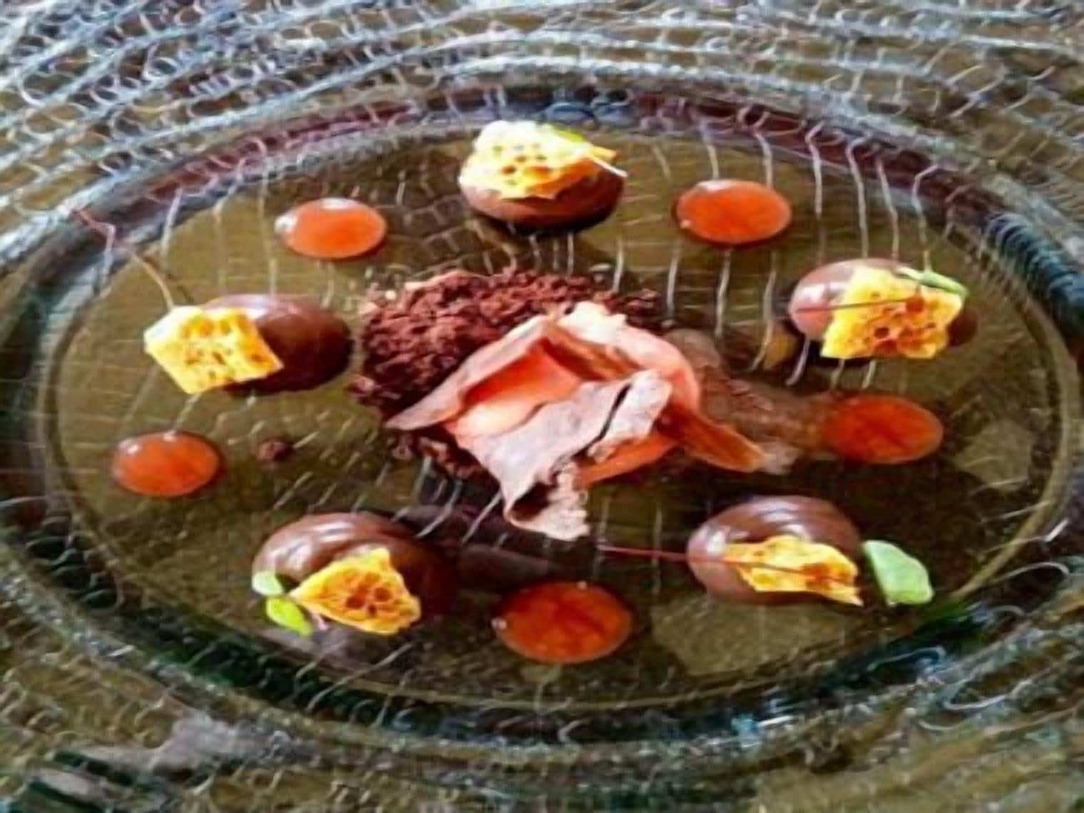 Une assiette de dessert avec divers fruits et un morceau de chocolat au centre.