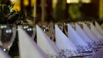 A row of wine glasses with white napkins, some with a decorative pattern, and a potted plant in the background.