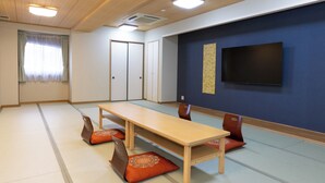 Une pièce de style japonais traditionnel, avec un sol recouvert de tatamis, une basse table en bois et des tapis de tatami agrémentés de coussins.