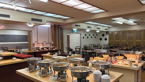 Un buffet proposant différents stands de nourriture, notamment des plats à réchauffer et des plateaux de mets variés.