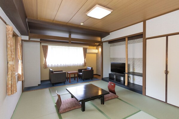 A traditional Japanese room with tatami flooring, a low table, seating, and a TV. - Itoen Hotel Hakone Yumoto (Hakone)