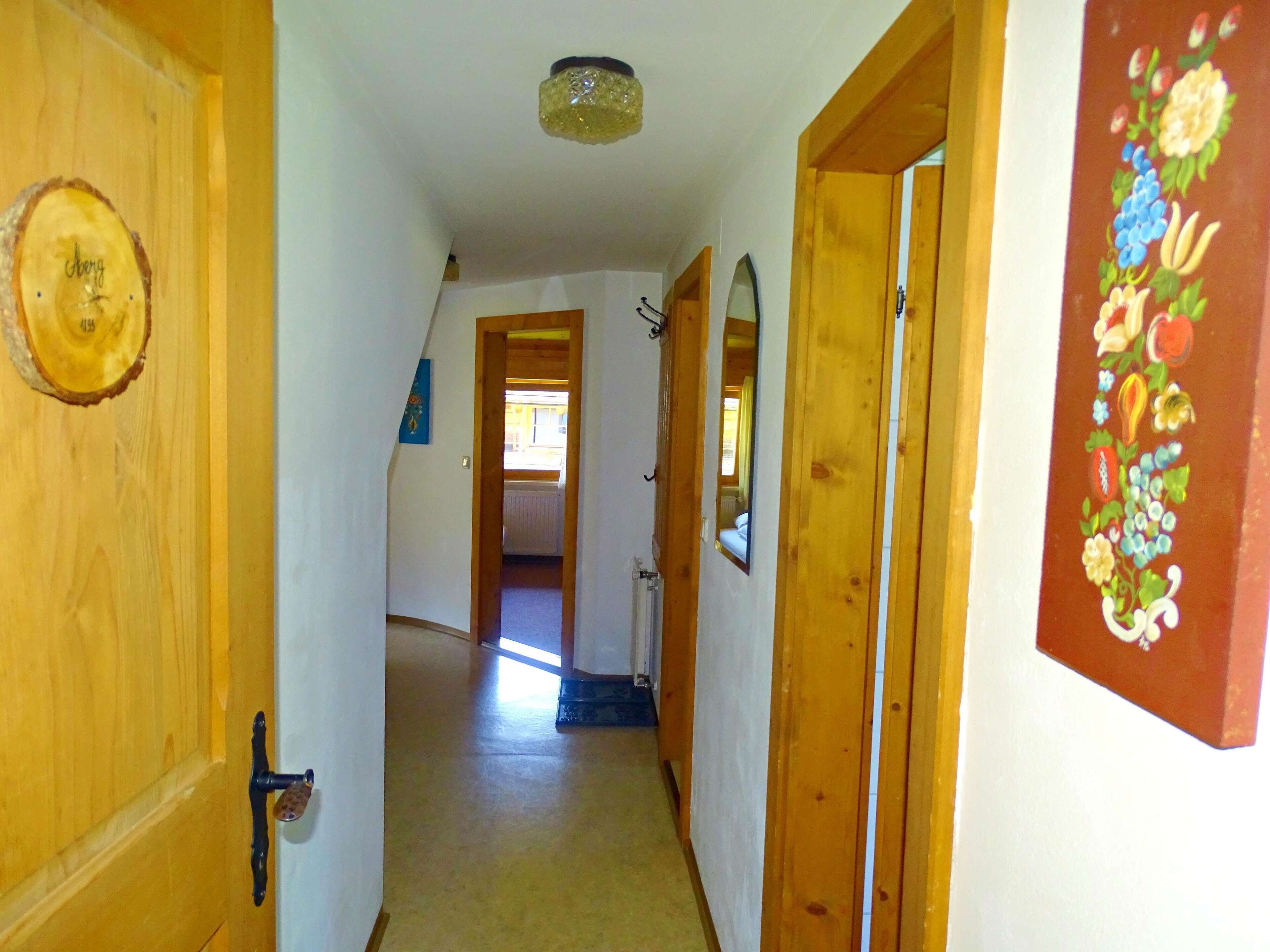 A narrow hallway with wooden doors and a ceiling light fixture.