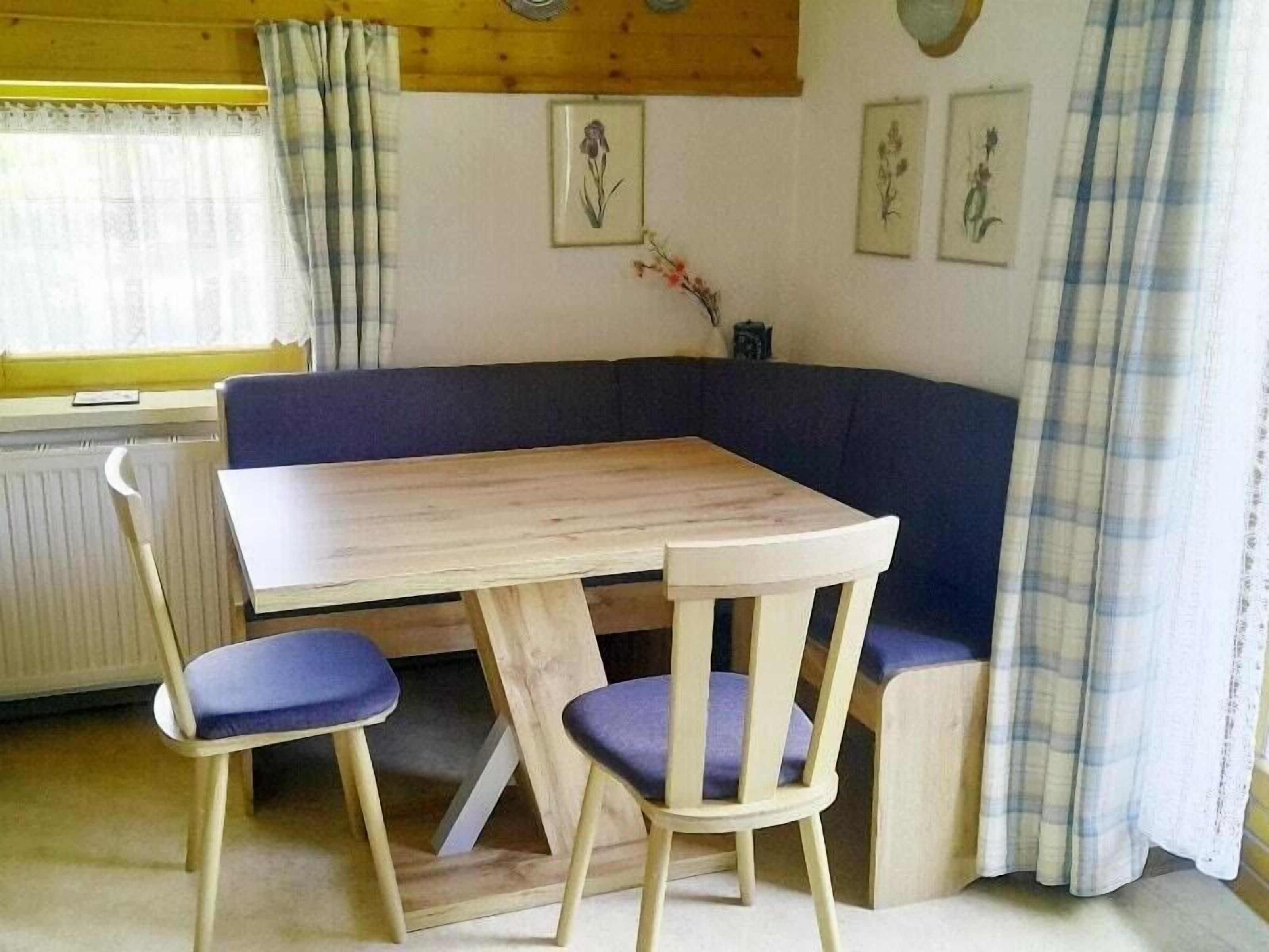 Ein Zimmer mit einem Holztisch, zwei Stühlen, einem blauen Sofa und einem Heizkörper.
