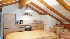 Una cocina compacta con armarios de madera, estufa, cafetera y lavabo.