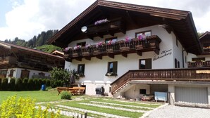 Un chalé tradicional con un balcón decorado con flores, una terraza de madera y vistas despejadas del paisaje circundante.