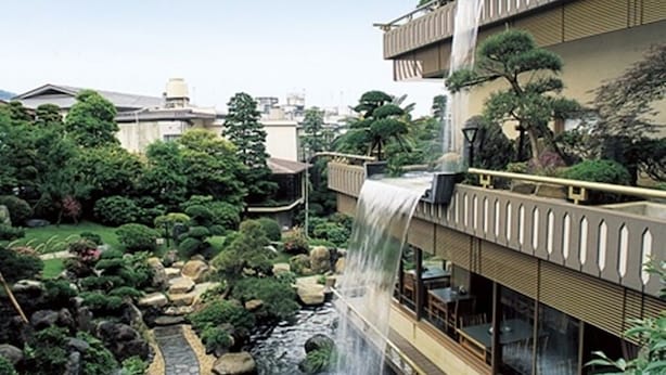 A traditional Japanese-style garden with a waterfall, stone pathway, and lush greenery. - Atami Kinjokan (Atami)