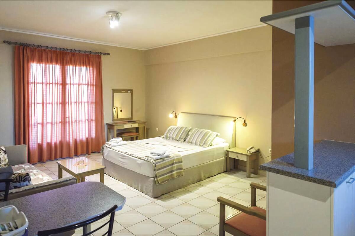 A hotel room with a bed, bedside table, lamp, and a small desk with a chair.