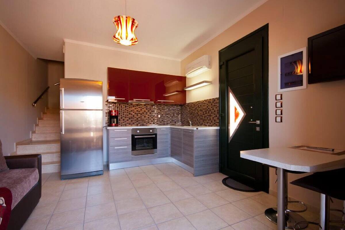 A modern kitchen with a built-in oven, a stainless steel refrigerator, and a tiled backsplash.