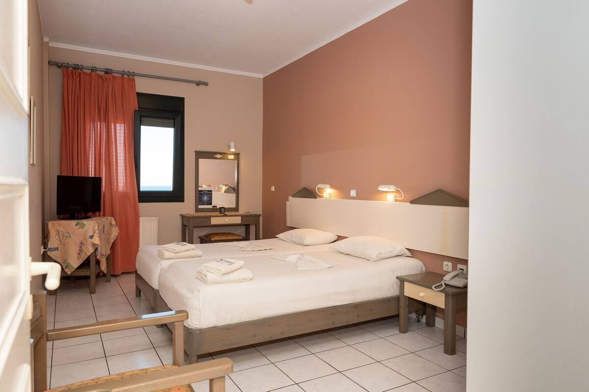 A hotel room with a bed, bedside table, lamp, and a television.
