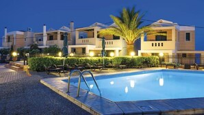 Un hotel moderno con piscina, zona de estar al aire libre y fachada bien iluminada.