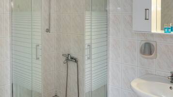 Une salle de bain moderne avec une douche à parois de verre, un lavabo blanc et un miroir au-dessus du lavabo.