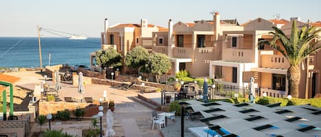 A coastal hotel with multiple balconies, outdoor seating, and a view of the sea.