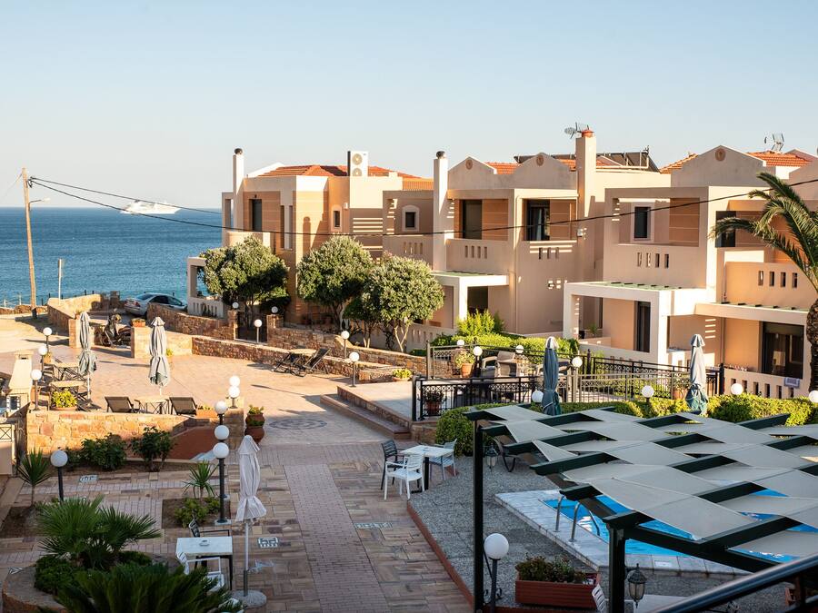 Un hotel frente al mar con varios balcones, mobiliario exterior y vistas al océano.