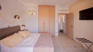 Habitación de hotel con cama, armario, televisión y lámpara fijada a la pared.