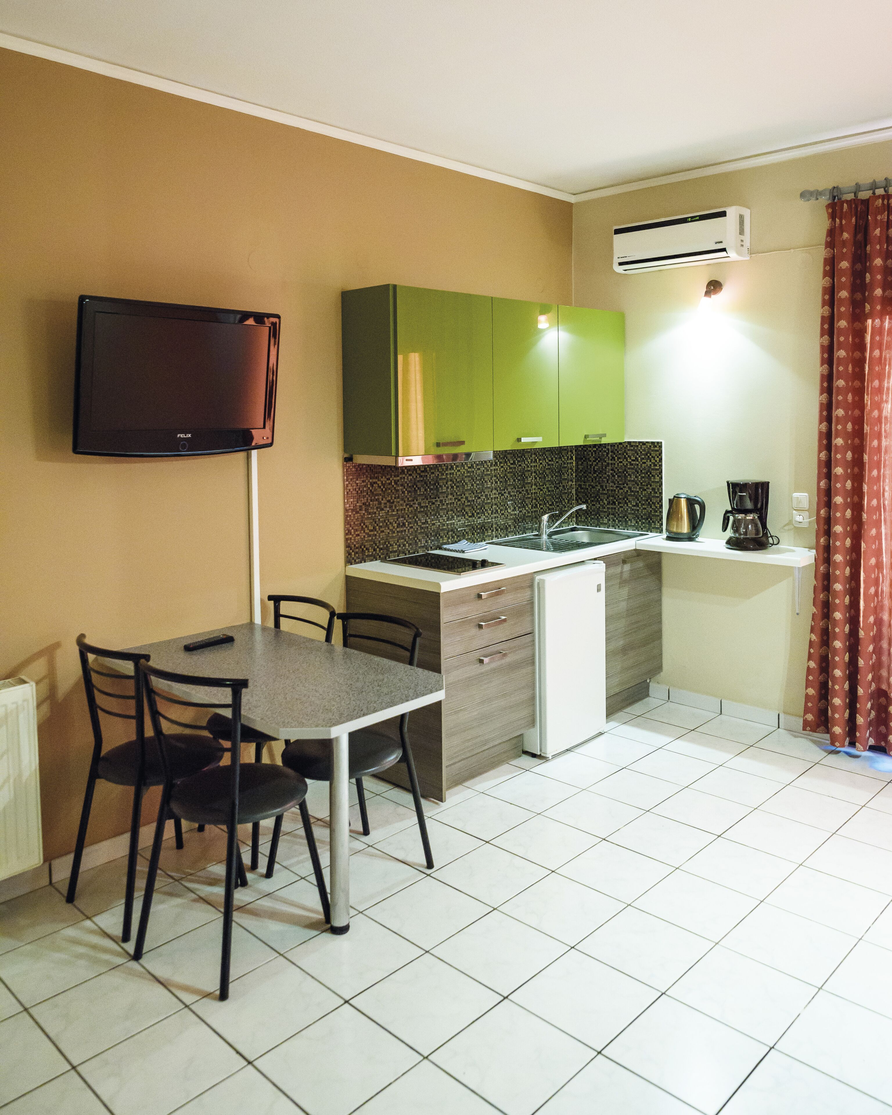 A compact kitchen with a dining area, a flat-screen TV, and a coffee maker.