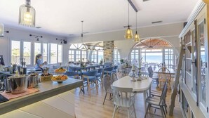 Una cocina amplia con ventanas grandes, una barra y un comedor con vistas al mar.