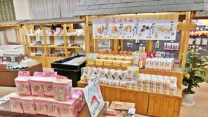 A variety of packaged goods displayed on wooden shelves and tables, including snacks and possibly food items. - Itoen Hotel Shikisai (Yugawara)