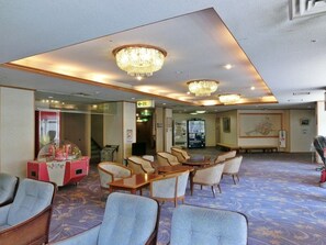 Rebedor d'hotel amb zona de seients, lluminàries penjants, una màquina expenedora i una paret amb una peça decorativa.
