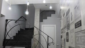 Una escalera con barandilla de metal negro, una puerta blanca en la parte superior y una pared con varios carteles.