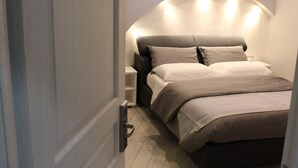 Un dormitorio con cama, mesitas de noche y una lámpara de pared curva.