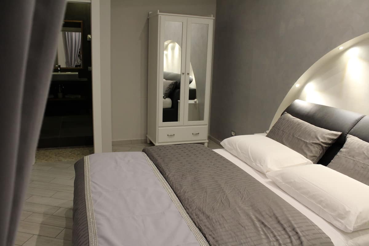 Un dormitorio con cama, armario y baño visible a través de una puerta abierta.