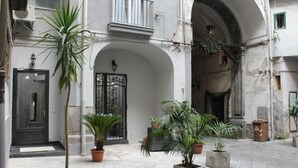 Un patio con plantas en macetas, una puerta y un balcón.