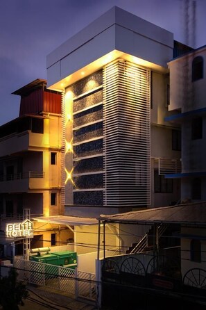 Un bâtiment d’hôtel moderne, caractérisé par une section verticale imposante agrémentée de lambris horizontaux, un espace sur le toit avec un conteneur végétalisé et une enseigne bien visible pour l’hôtel.